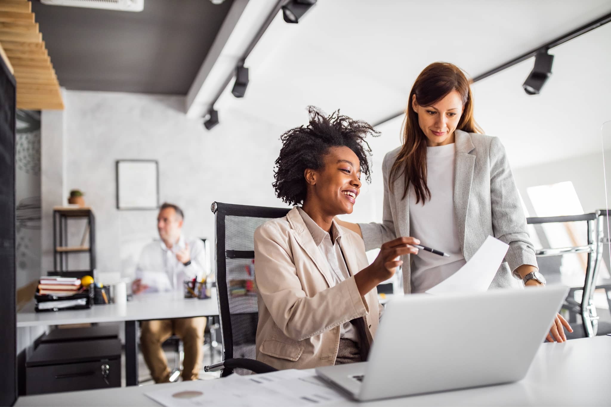 A group of two female workers discussing at the office - Pearson TalentLens