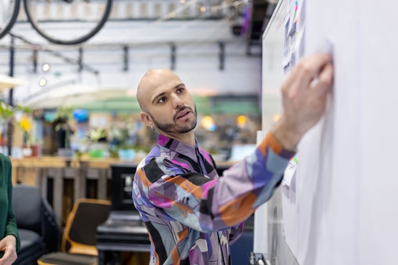 Un homme écrivant sur un tableau blanc - Pearson TalentLens