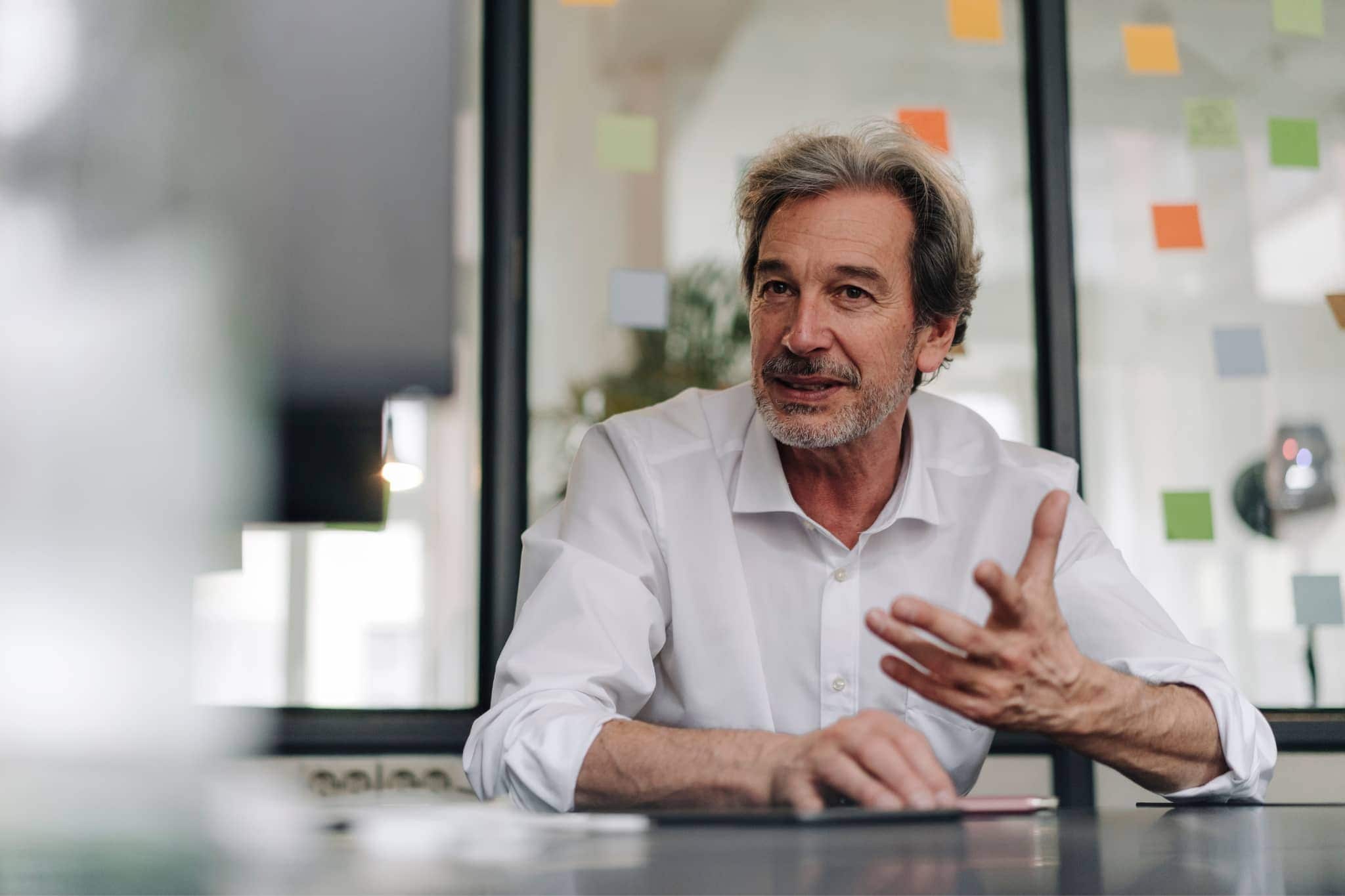 A male worker discussing at a table - Pearson TalentLens