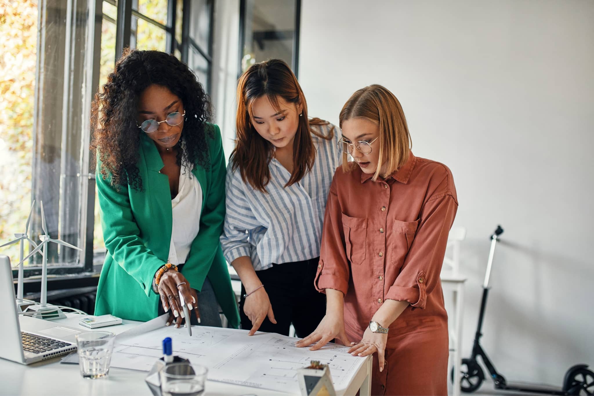 A group of three female coworkers brainstorming - Pearson TalentLens