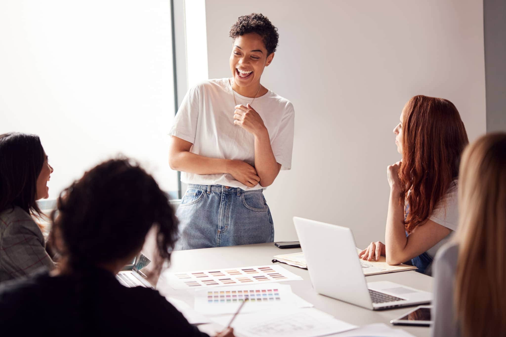 A group of coworkers leaded by a female manager laughing - Pearson TalentLens