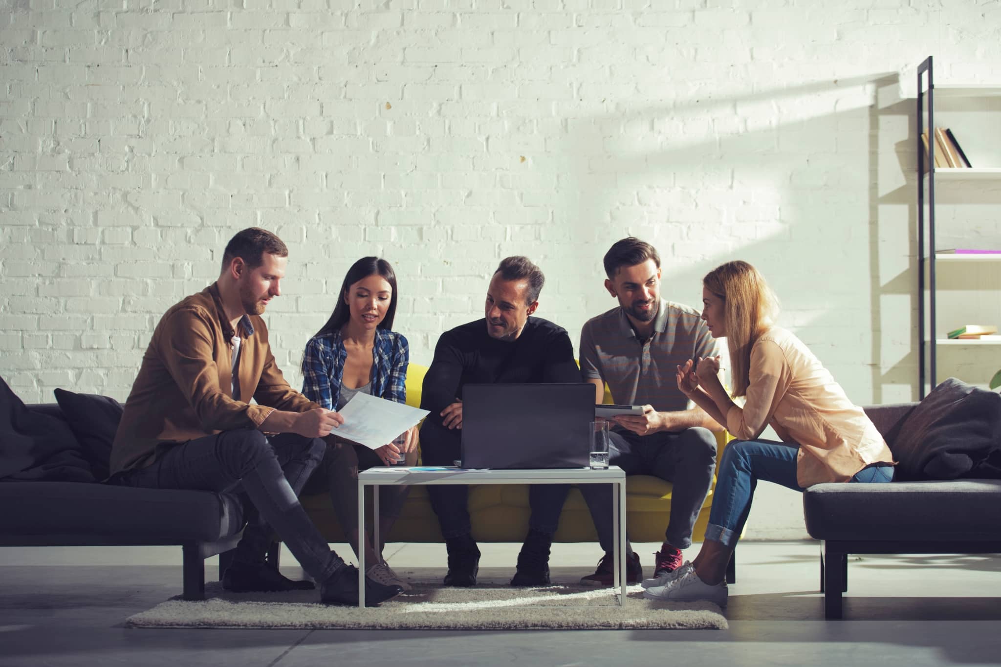 AI solutions - group of colleagues discussing around laptop - Pearson TalentLens